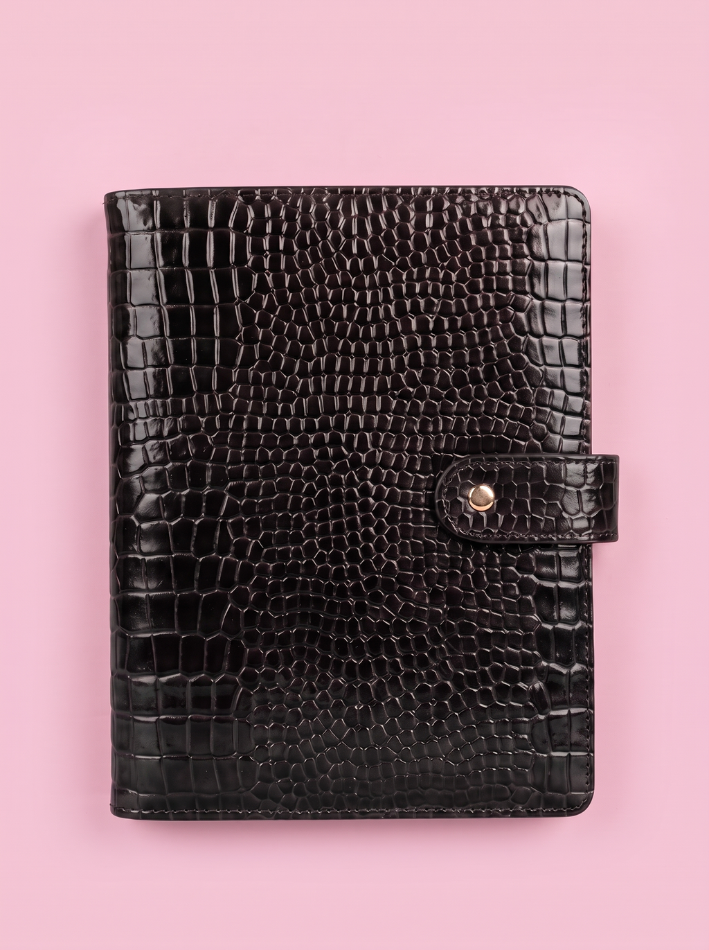 Black crocodile-print A5 six-ring planner by Cavie, flat-lay on a pink background