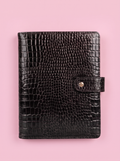 Black crocodile-print A5 six-ring planner by Cavie, flat-lay on a pink background