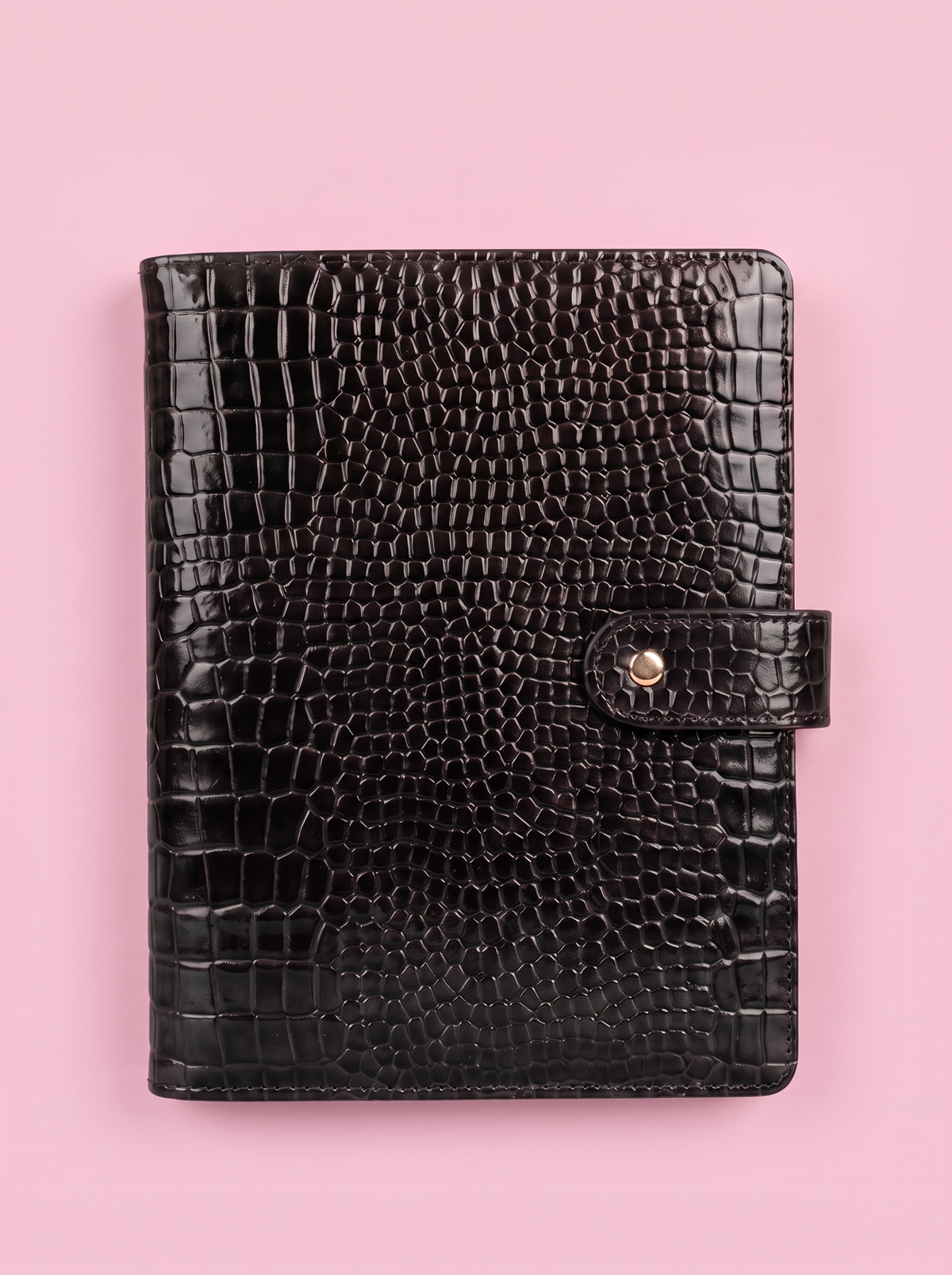 Black crocodile-print A5 six-ring planner by Cavie, flat-lay on a pink background